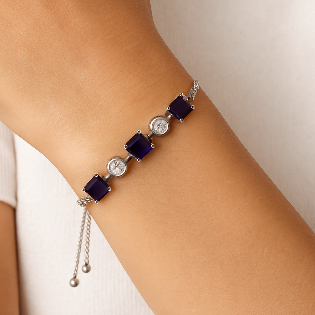 Silver bracelet with blue gemstones on a wrist against a neutral background