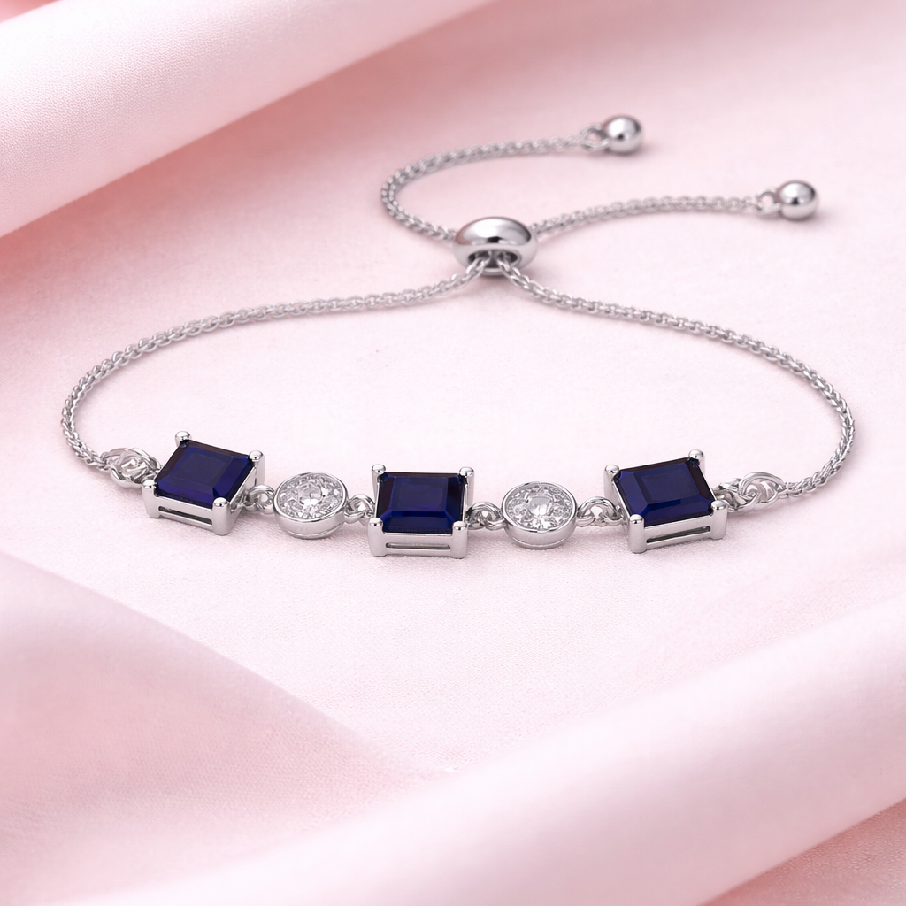 Silver bracelet with blue gemstones on a pink fabric background