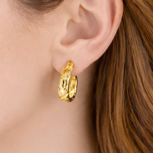 Gold hoop earrings worn by a person with brown hair.