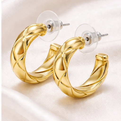 Gold hoop earrings on a light fabric background